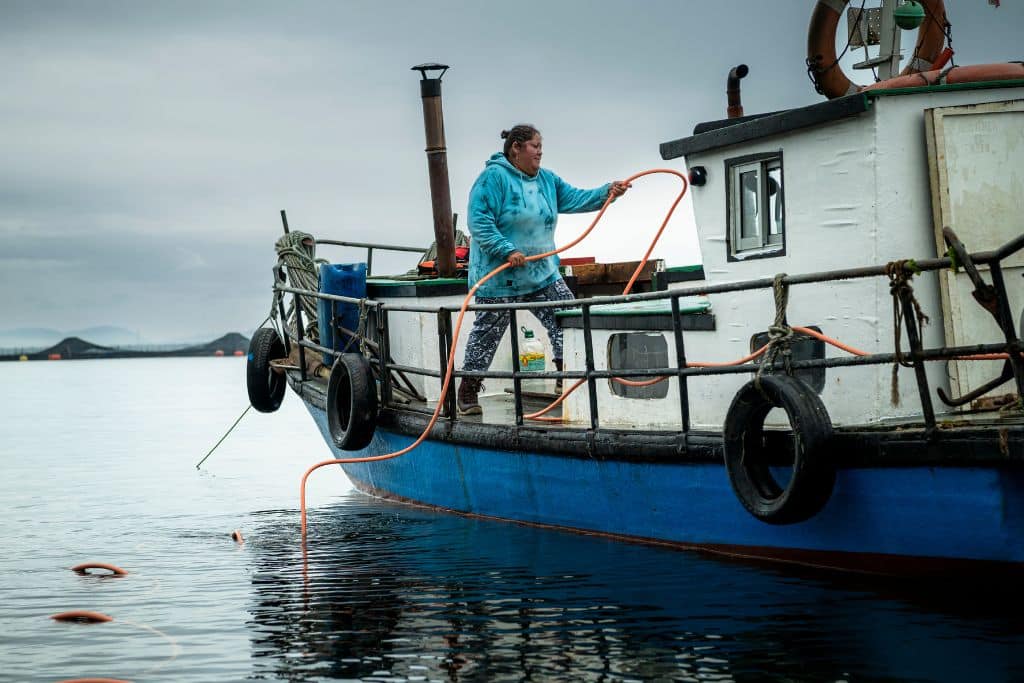 Carmen donne un tuyau d’oxygène orange à son mari, Jaime, qui va plonger au fond de la mer.