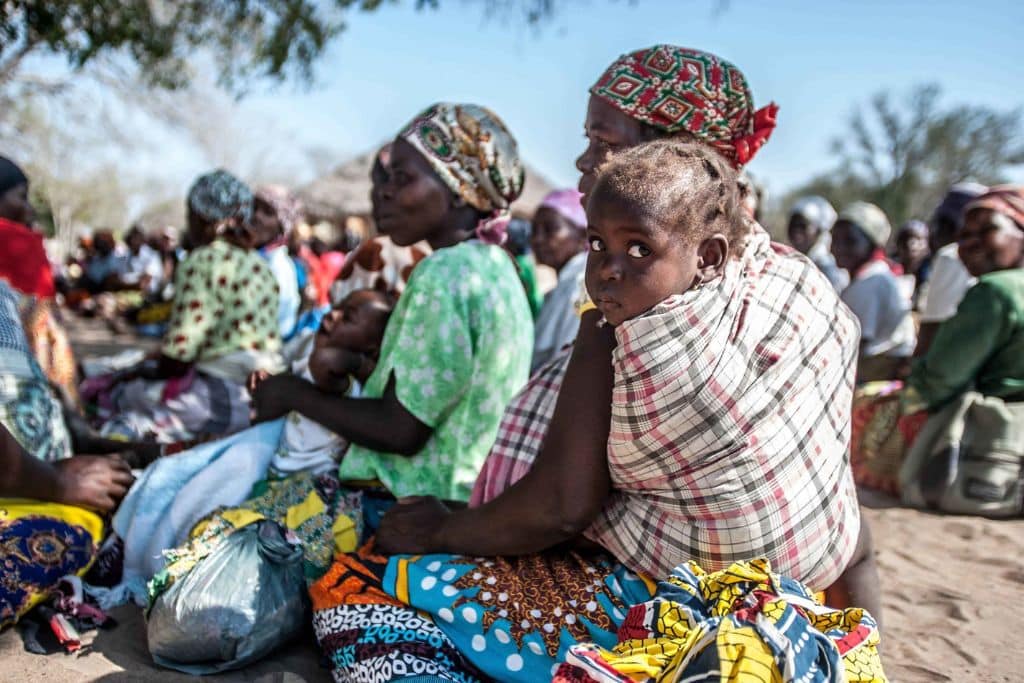 Mères et enfants patientant dans la communauté de Changanine au Mozambique pour récupérer leurs graines auprès de la Croix-Rouge lors d’une sécheresse.