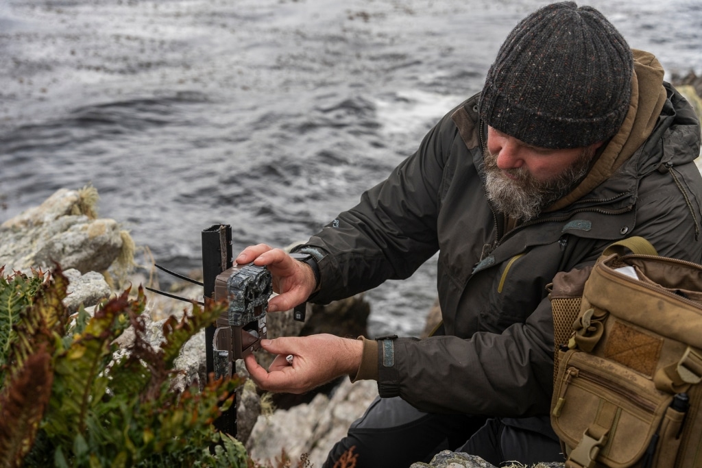 Ross James of Falklands Conservation, setting camera traps on the coastline.