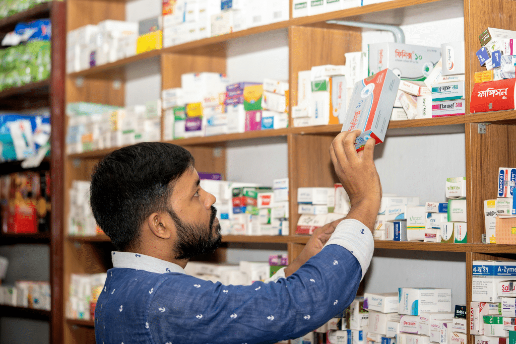 A man looks at medicines arranged on a shelf at a pharmacy.