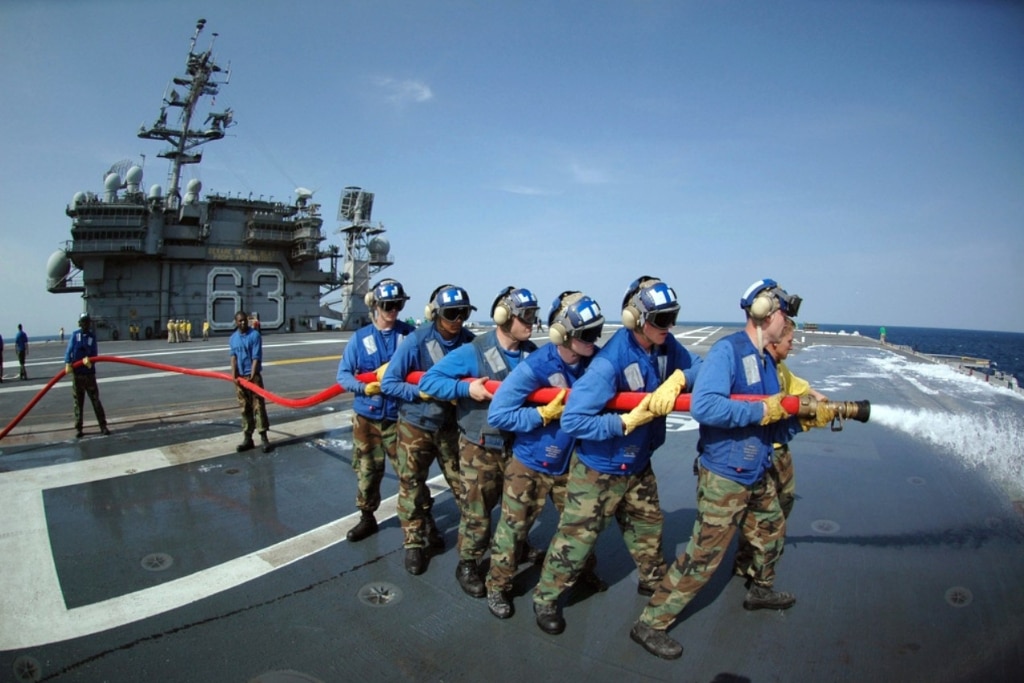 US Navy (USN) Air Department personnel wash Aqueous Film Form Forming Foam (AFFF) off the flight deck of the USN Aircraft Carrier USS KITTY HAWK (CV 63) while participating in the ship's firefighting drills.