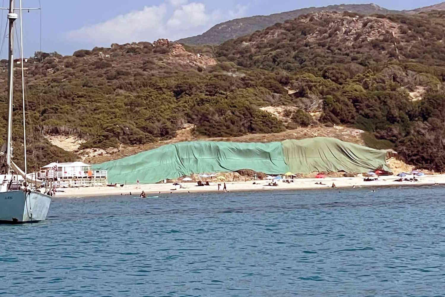 Une vieille décharge illégale émerge d'une plage de Sardaigne et la commune la couvre de grandes bâches vertes